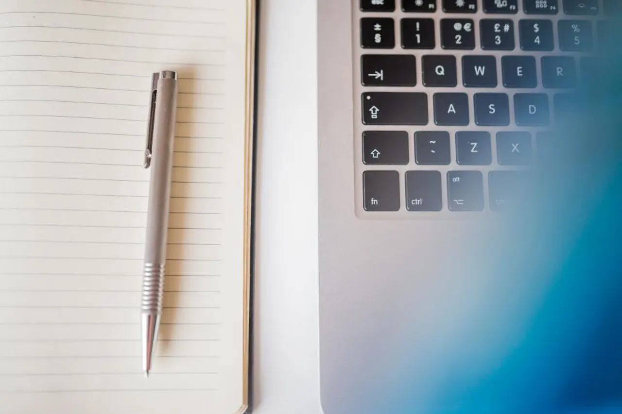Notebook and pen beside a laptop keyboard, ready for discovery notes